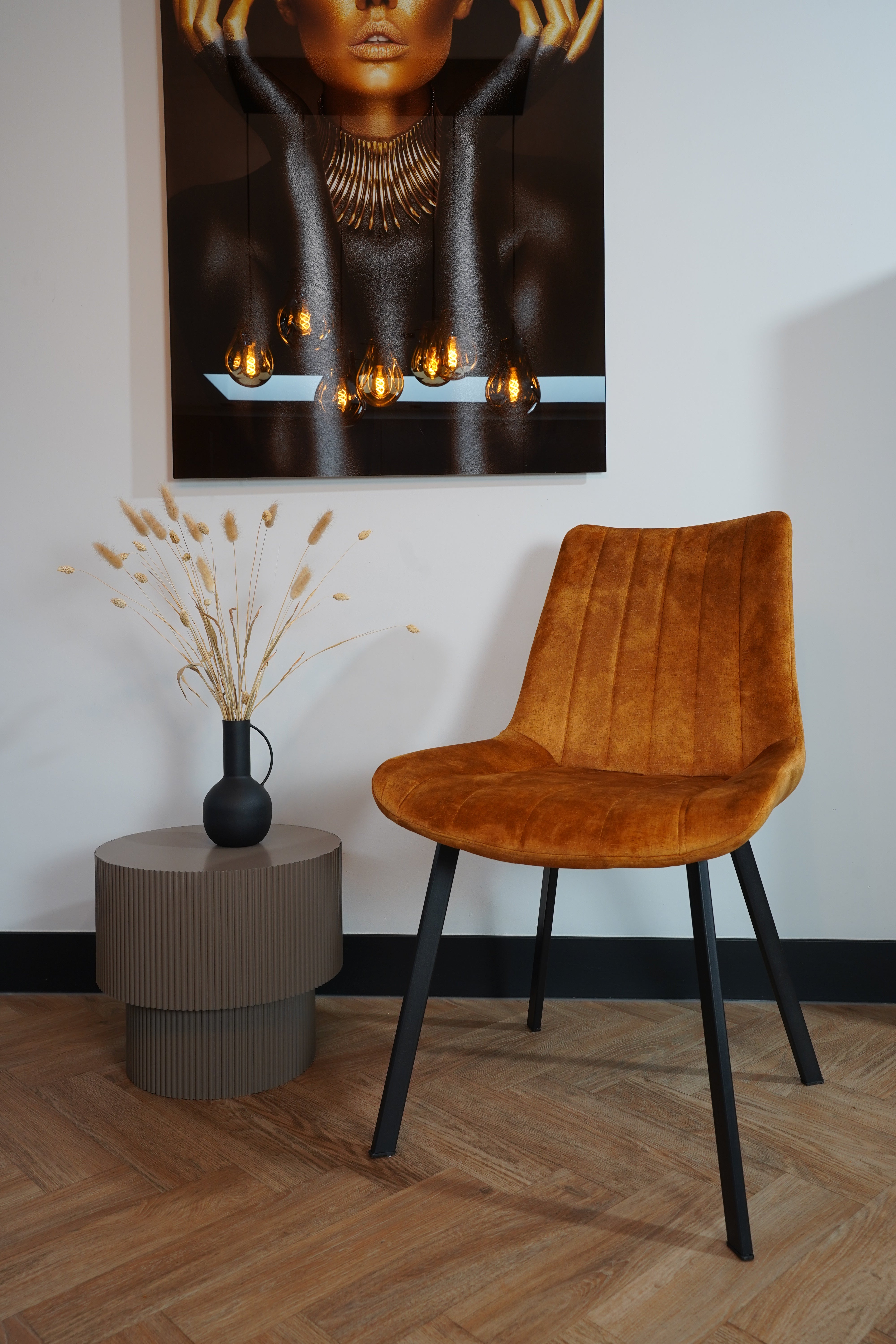 Modern living room featuring Eetkamerstoel Marilene velvet chair with unique design, next to a minimalist side table and wall art.